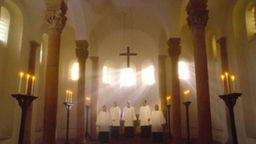 Vor dem Altar stehen 5 Messdiener, über ihnen hängt ein Kreuz, die Kapelle ist lichtdurchflutet.