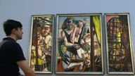 Mann sieht das Gemälde Perseus-Triptychon von Max Beckmann an