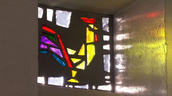 Glasfenster in St. Juliana mit einem Hahn