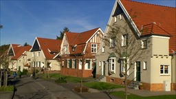 links eine Straße, rechts sieht man vier individuelle Häuser