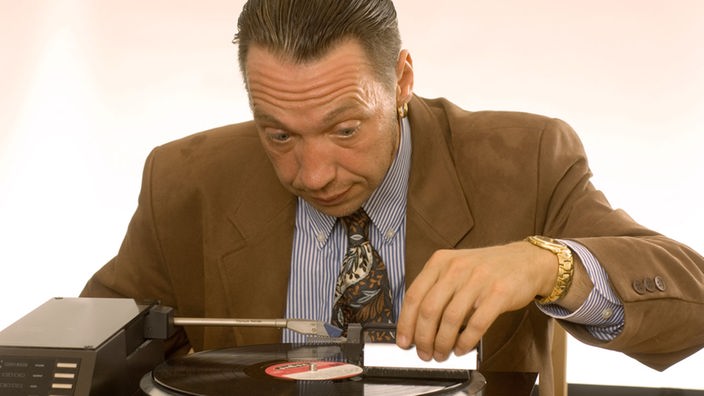 Andreas Herkendell reinigt Schallplatte vorsichtig mit einem kleinen Besen