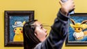 Eine Besucherin fotografiert sich selbst vor Pokémon-Gemälden im Van-Gogh-Stil.