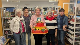 Bücherleiterin Anette Göhler (Mitte) und Mitarbeiterinnen der St. Martinus Bücherei Stommeln halten eine Geburtstagstorte.