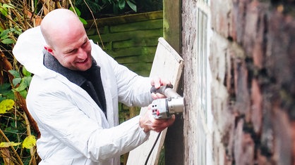 Moderator Alexander Brauer arbeitet an einer Hauswand.