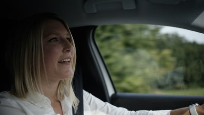 Dorfcoach Laura Schuster sitzt im Auto und fährt.