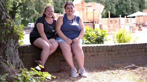 Michelle Langer und Charleen Venten sitzen auf einer Mauer