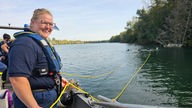 Bergungstaucherin Katharina Wolff steht auf einem Boot und hält eine gelbe Leine, an der der Tauchanwärter befestigt ist