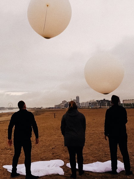 Bestatter lassen Ballons mit der Asche eines Verstorbenen am Strand aufsteigen.