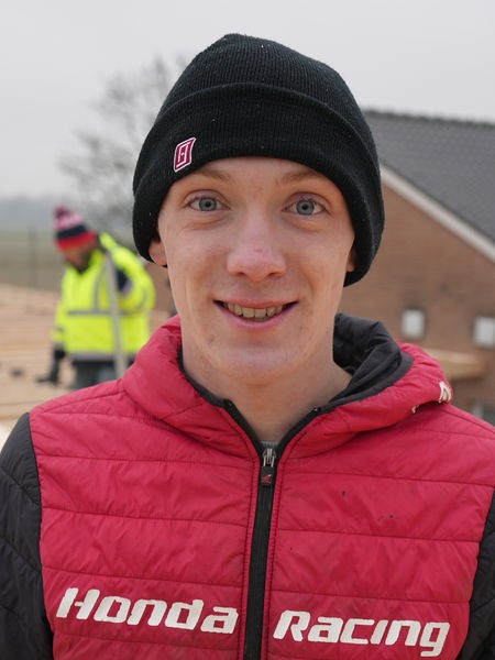 Jungee Mann mit einer roten Weste steht auf einer Baustelle