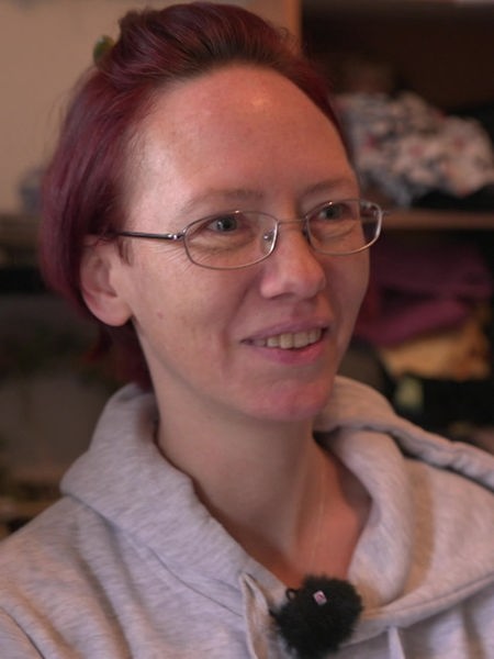 Eine Frau mit dunkelroten Haaren steht in einem Raum mit gefüllten Regalen