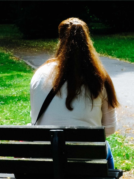 Sandra Riesener, eine Frau mit braunen langen Haaren, sitzt auf einer Bank