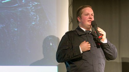 Lukas Ritgens auf einer Bühne mit einem Mikrofon in der Hand