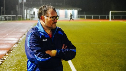 Ein Mann in Trainingskleidung am Spielfeldrand