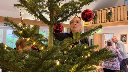 Gudrun Högemann schmückt einen Weihnachtsbaum