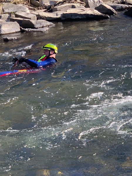 Ein Strömungsretter schwimmt mit Schutzkleidung in einem Fluss