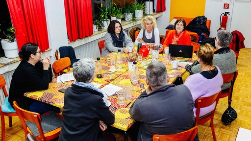 Mehrere Erwachsene sitzen an einem großen Tisch 