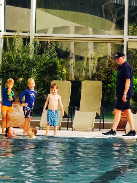 Ein Mann und mehrere Kinder stehen an einem Schwimmbeckenrand. 