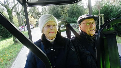 Ein älteres Paar sitzt in einem Elektrocart