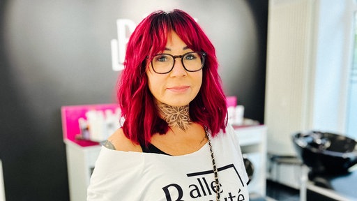 Eine Frau mit pink gefärbten Haaren steht in einem Friseursalon