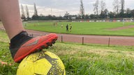 Ein schwarz-roter Fußballschuh und ein gelber Fußball