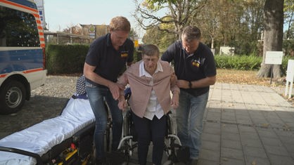 Günther Kemper hilft einer Patientin beim Gehen - auf dem Weg zu ihrem letzten Wunsch