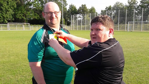 Jens Hotze und Benny Sildatke helfen sich gegenseitig auf dem Fußballplatz