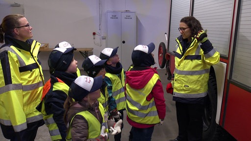 Kinder stehen mit Betreuerinnen vor einem Einsatzfahrzeug der Feuerwehr