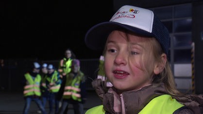 Ein sechsjähriges Mädchen mit Kappe und Warnweste