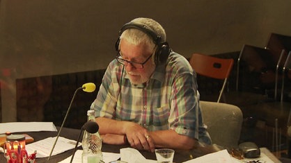 Moderator Wolfgang Nagel sitzt am Mikrofon und moderiert