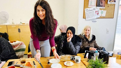 Sozialarbeiterin Bilge Akbulut verteilt kuchen an die Teilnehmerinnen des Mutcafés.