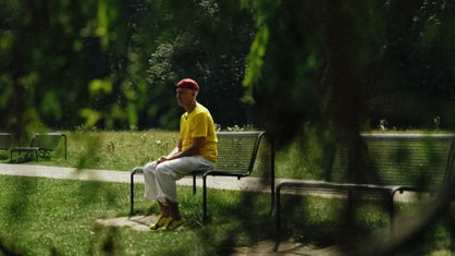 Florian Ditges sitzt auf einer Bank in einem Park