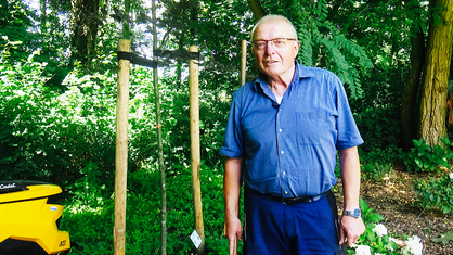 Robert Klein in der Halbtotalen im Garten des Nikolausklosters. Hinter ihm junge gestützte Bäume