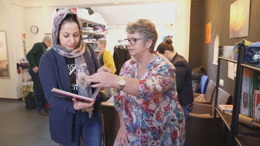 Ursula Lorke zeigt einer jungen Frau etwas in einem Buch