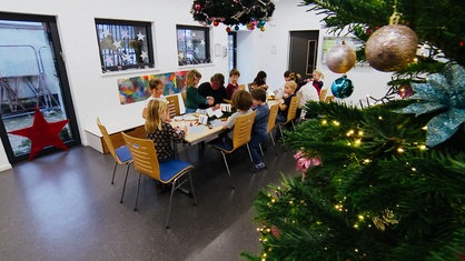 In einer Kita sitzen mehrere Kinder an einem Tisch und basteln 