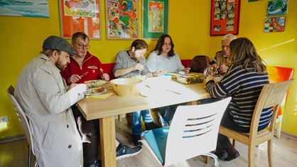 Mehrere Menschen sitzen an einem Tisch und essen gemeinsam Grünkohl