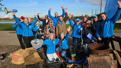Ein Gruppenfoto mit allen Helferinnen und Helfern der Rheinsäuberung mit dem gesammelten Müll