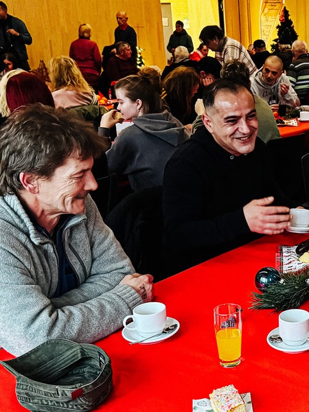 Erkan Nuran sitzt mit drei seiner Freunden am Tisch. Der Tisch befindet sich in einem gut gefüllten Saal.