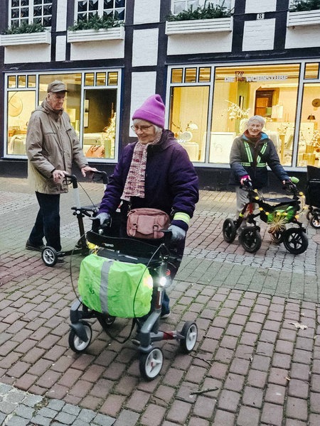 Die Innenstadt einer Kleinstadt. Mehrere Senioren mit Rollatoren gehen im Kreis