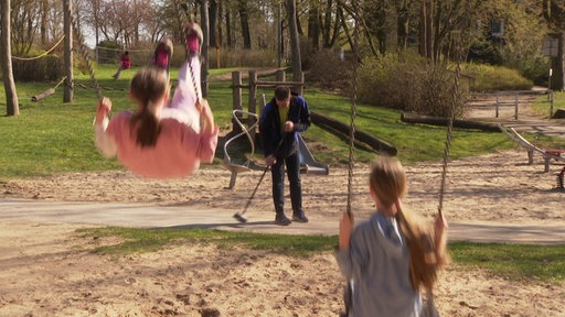 Mann fegt einen Spielplatz