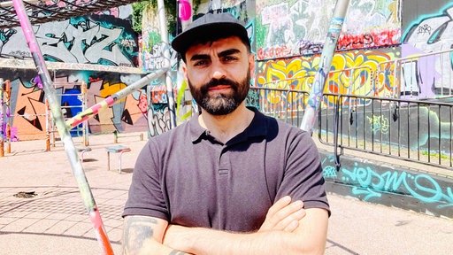 Hussein Shahin vor einem Hintergrund mit Graffitti.