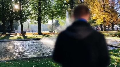 Ein Mann steht im Park. Sein Gesicht ist zensiert. 