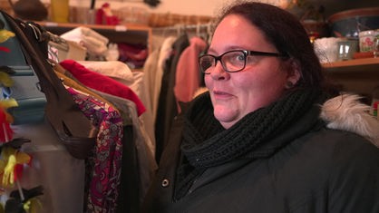 Eine Frau mit dunkelbraunen Haaren und Brille steht im Warenlager