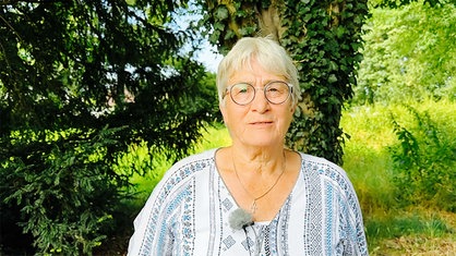 Angelika Lennertz steht vor einem Baum und schaut in die Kamera.