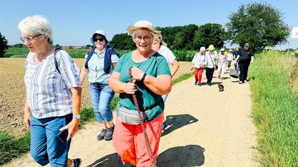 Die Teilnehmenden des Trauerspaziergangs gehen über einen Feldweg.