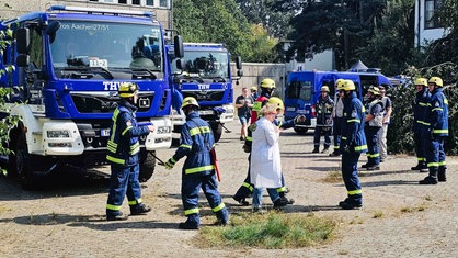 Die Lehrerin wird von mehreren THW-Helfern nach draußen begleitet.