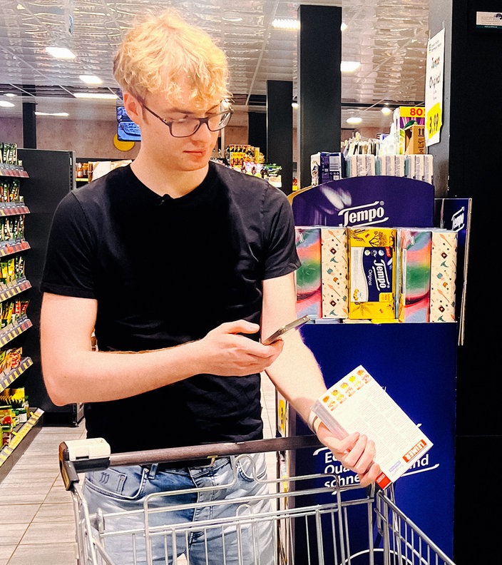 Jonah Hadt scannt in einem Supermarkt ein Produkt mit seiner App.