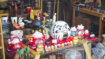 Schaufenster mit traditionell japanischen Winkekatzen und Teekannen