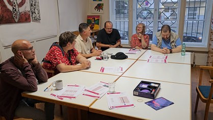 Gehinrtraining-Gruppe sitzt am Tisch und löst Aufgaben