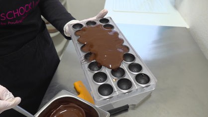 Flüssige Schokolade wird in eine Form gefüllt.