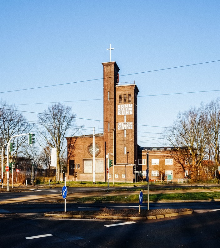 Eine Kirche an einer Straße, die von Bäumen umgeben ist 